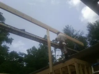 Carpenter setting a ridge beam over a new addition frame — Ice Dam Removal by Roofing Brothers in Matamoras