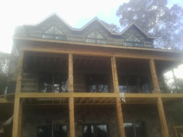 Dormers and porch framing on a large log home under construction — Roof Coating work by our crew in Matamoras