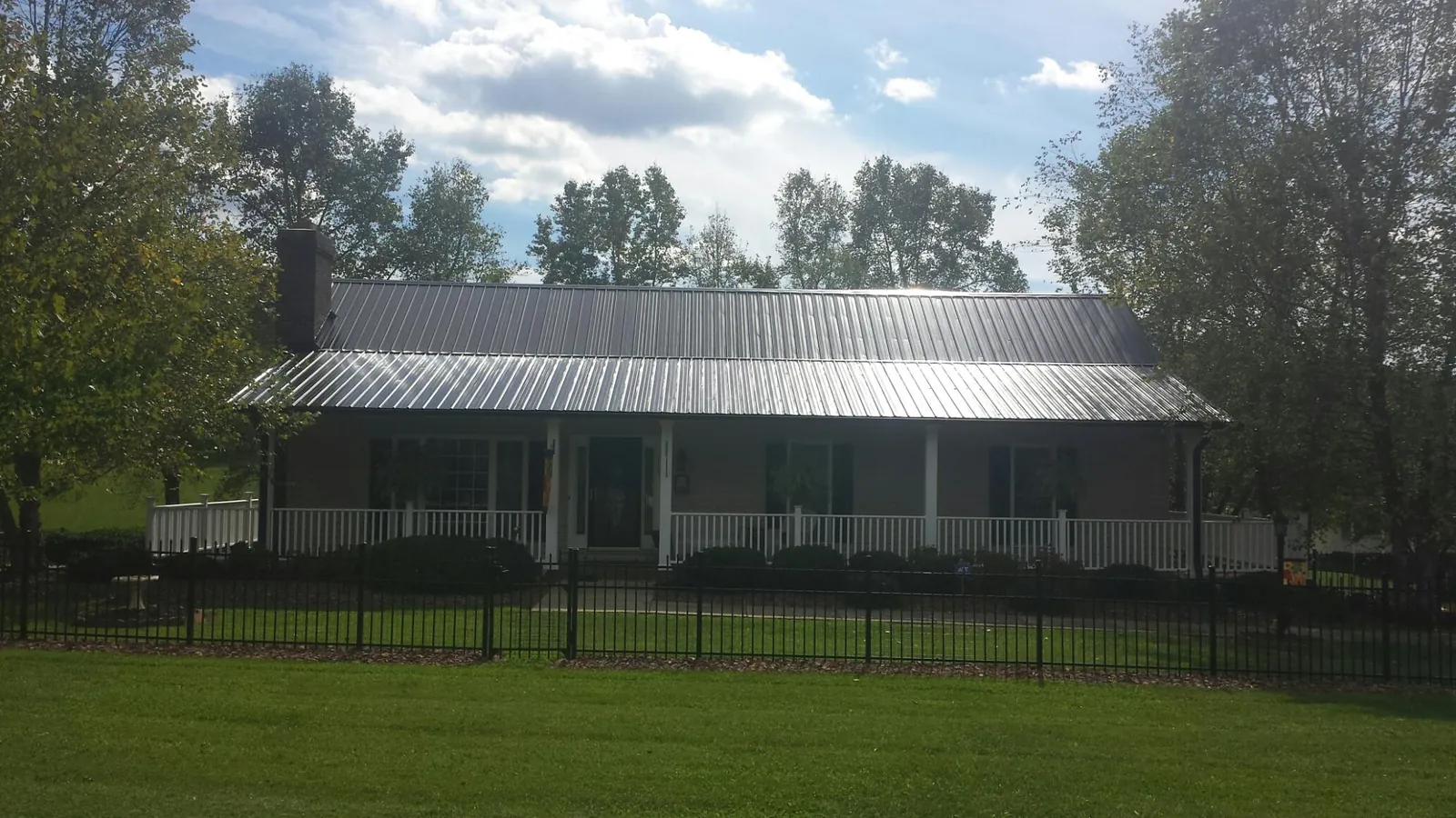 Gray metal roof on a brick ranch with a full width front porch — Gutter Guard Installation work by our crew in Matamoras